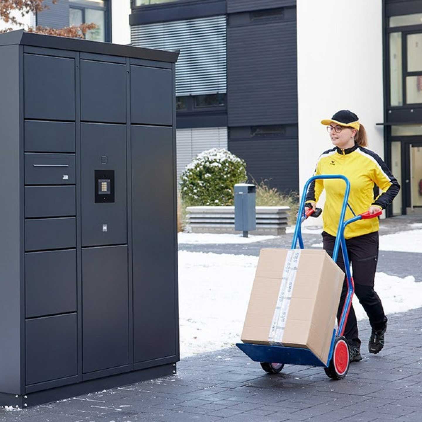 Eine Paketfahrerin liefert neue Pakete für die hauseigene Packstation